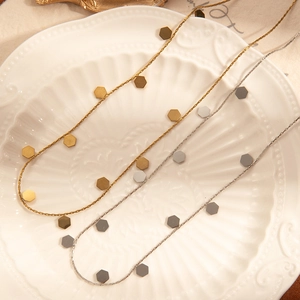 Close-up of minimalist gold and silver stainless steel chains with hexagonal charms