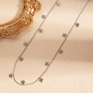 Detail of silver O-chain necklace featuring multiple brushed metal bird-shaped charms