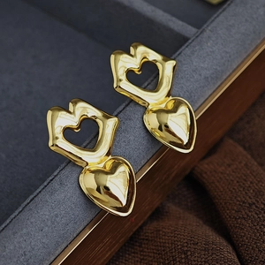 Makroaufnahme goldener Herz- und Lippenohrringe auf einer luxuriösen Schmuckschatulle