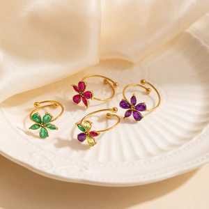 Elegant gold titanium steel rings with colorful five-petal zircon flowers on a white plate