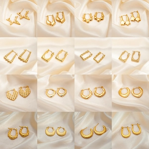 Collection of sixteen pairs of textured gold titanium steel earrings on silk background
