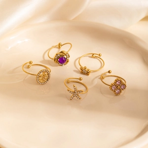 Golden Tree of Life and star rings set with purple gemstones on ceramic tray