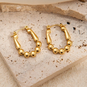 Macro view of gold U-shaped earrings featuring five polished beads on stone stand
