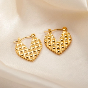 Detail of gold heart hoop earrings with waffle texture on white silk background