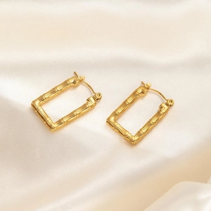 Detail shot of golden bamboo texture rectangular hoop earrings on beige silk fabric