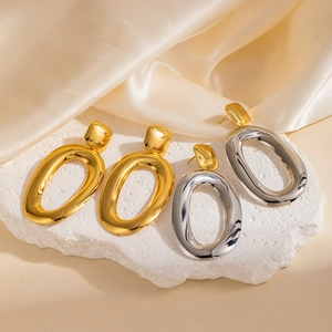 Boucles d'oreilles ovales dorées et argentées sur pierre blanche et fond satiné