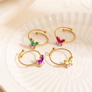 Set of four adjustable gold butterfly rings with colorful cubic zirconia on a ceramic tray