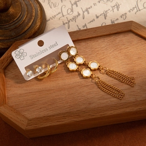 Détail d'un ensemble de boucles d'oreilles en acier avec perles et pompons