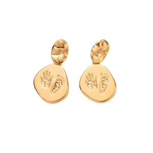 Détail de boucles d'oreilles dorées avec disques texturés et empreintes de bébé gravées