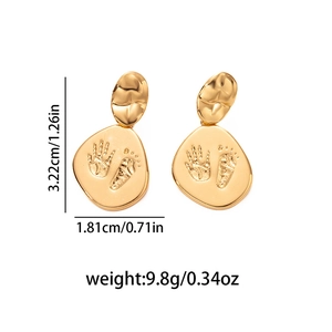 Détail de boucles d'oreilles ovales dorées avec gravure empreinte bébé et mesures