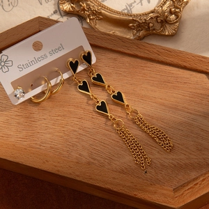Détail d'un ensemble de boucles d'oreilles en acier avec pompon cœur sur bois vintage