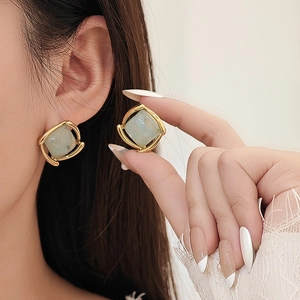 Boucles d'oreilles carrées dorées avec pierre verte portées par un mannequin