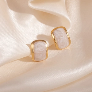 Vue macro de boucles d'oreilles dorées avec texture marbrée sur tissu en soie