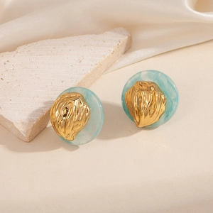 Boucles d'oreilles dorées goutte d'eau avec résine marbre bleu sur fond de soie