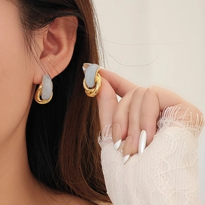 Boucles d'oreilles géométriques dorées avec pierre grise portées par un mannequin femme