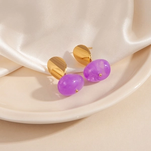 Gros plan sur les boucles d'oreilles cœur en métal doré et résine violette marbrée