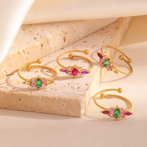 Détail de bagues torsadées dorées avec incrustations de zircon coloré sur pierre