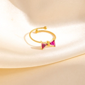 Macro d'une bague dorée avec nœud en zircon rouge et détails de l'anneau perlé