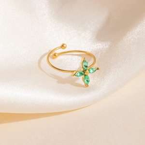 Détail d'une bague ajustable dorée ornée d'un trèfle en zircon vert sur tissu en soie
