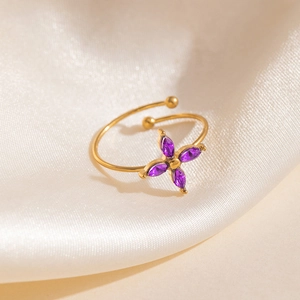 Gros plan d'une bague trèfle dorée avec zircons violets sur soie beige