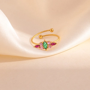 Gros plan d'une bague torsadée dorée ornée d'une pierre marquise verte et zircons