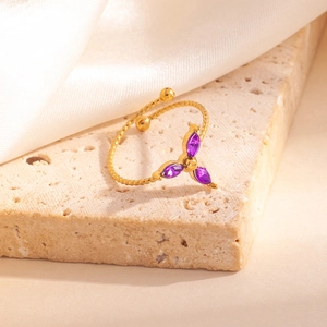 Détail d'une bague ouverte dorée torsadée avec trois pierres marquises violettes
