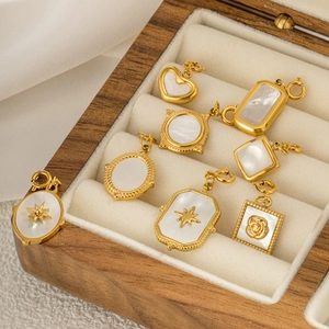 Eight gold-plated jewelry pendants with white shell inlay shown in a luxury wooden box
