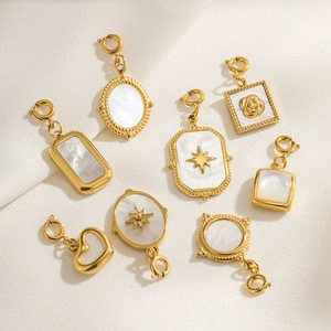 Set of eight gold plated jewelry pendants with pearl inlay on white silk background