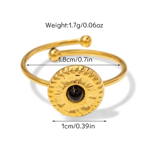 Détail d'une bague dorée ajustable avec texture soleil et perle noire centrale