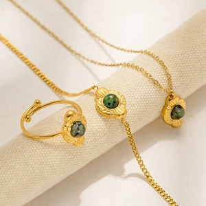 Detail of vintage gold-plated jewelry set with green stones and sunburst engravings