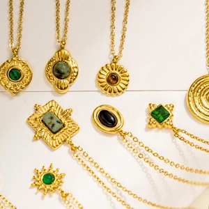 Detail view of vintage 18K gold plated necklaces with emerald and natural stone pendants