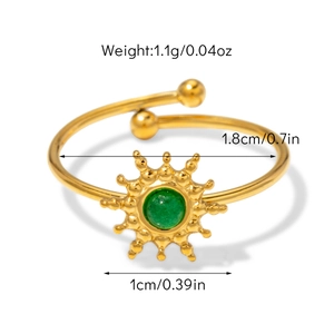 Détail d'une bague soleil dorée avec pierre verte centrale et anneau ajustable