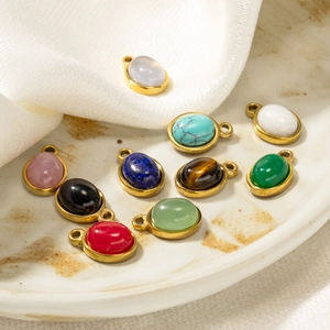 Oval natural stone pendants with gold frames displayed on elegant marble and silk