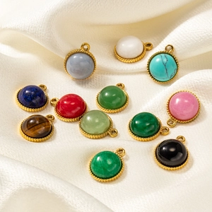 Set of 12 circular natural stone pendants with gold textured borders on white silk fabric
