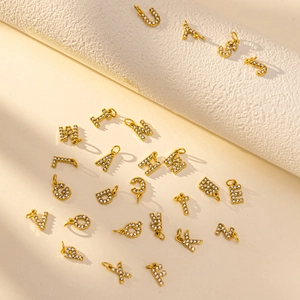 Macro shot of gold-plated A-Z letter pendants with micro-paved rhinestones for jewelry making