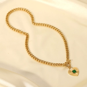 Collar retro con cierre OT dorado y colgante de corazón verde sobre seda marfil
