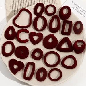 Macro shot of assorted vintage red flocked heart and geometric jewelry charms on a white plate