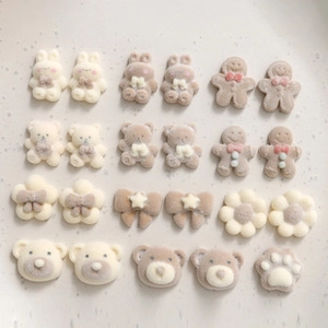 Detailed view of matte cream and brown resin charms in bear and flower shapes for DIY