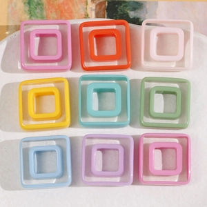 Colorful geometric square resin charms for DIY hair clips displayed on a white tray