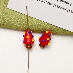 Macro detail of handmade red glass mushroom beads for DIY jewelry with center perforation