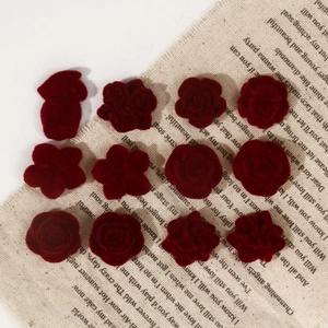 Macro shot of dark red velvet rose resin cabochons on natural linen fabric background