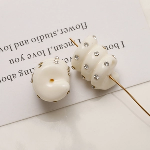 Close-up of cream spiral beads with rhinestones showing through-hole for DIY earrings