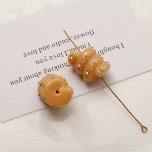 Detail of amber spiral bead with crystal rhinestones and a gold pin for jewelry making