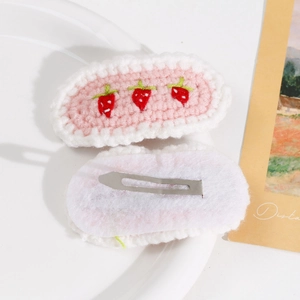 Detail showing pink crochet strawberry hair clip with metal BB clip and fabric backing