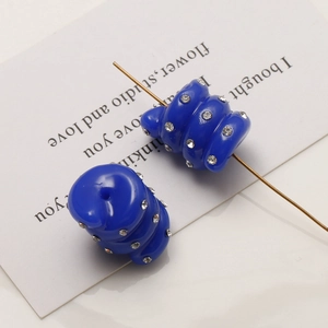 Detail of blue spiral resin beads with inlaid rhinestones on a metal jewelry pin