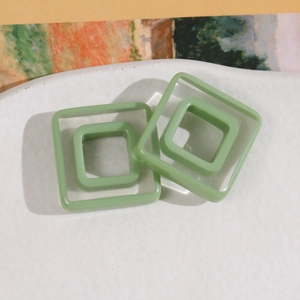Detail of green double-layer square resin geometric studs on white ceramic plate