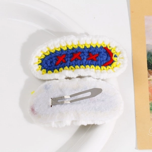 Detailed view of hand-knitted floral hair clips with secure metal BB clips on white felt