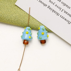 Close-up of handmade blue mushroom glass beads with colorful dots for DIY jewelry
