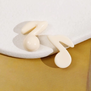 Vista macro di ciondoli a nota musicale in resina crema su vassoio bianco e giallo