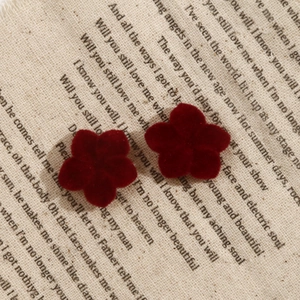 Detail of dark red velvet flower resin charms for jewelry DIY on vintage fabric background